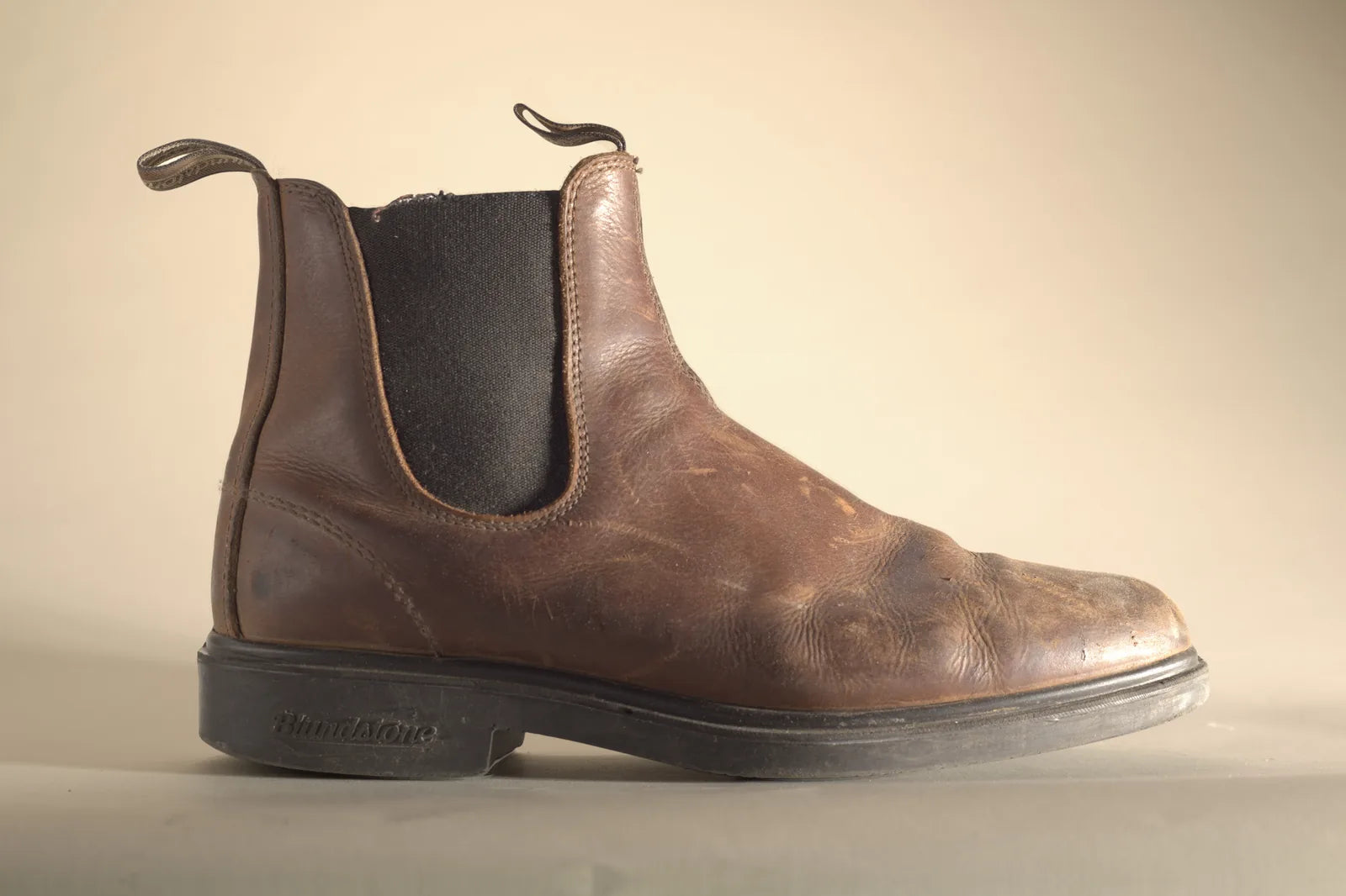 Brown Blundstone boot from the outside, with a pale, scuffed toe and scratches, before Boot Wax