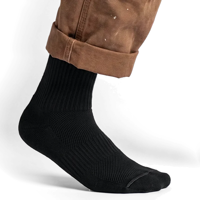 A black Merino Boot Sock under a rolled canvas work pant, mid-step